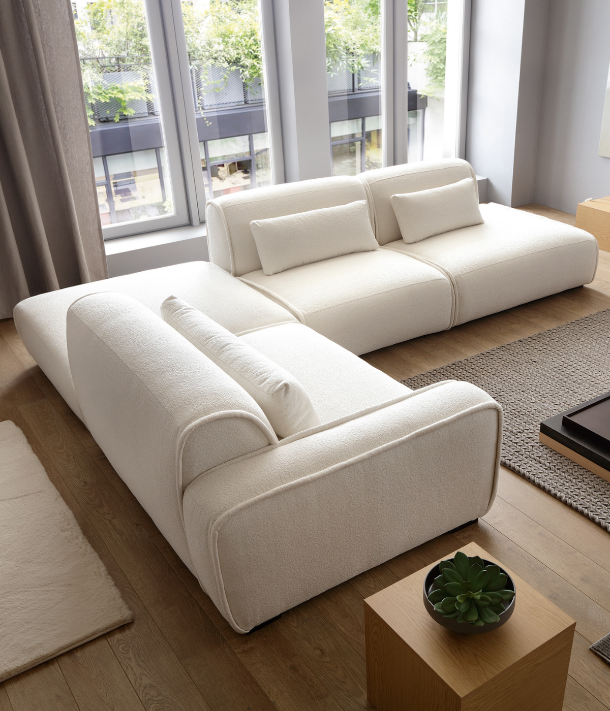 Narożnik Panda w układzie L z dużą pufą Ho wewnątrz układu, w jasnej tkaninie