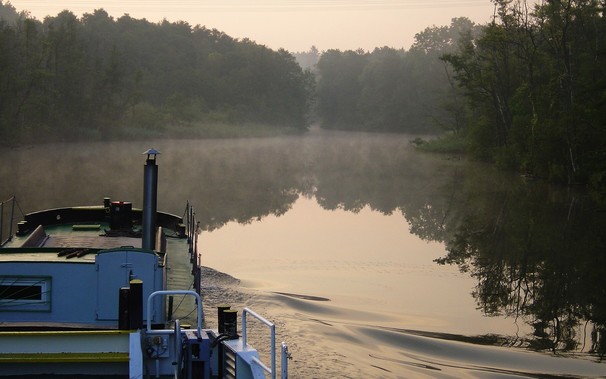 Ein Schiff befährt die Obere Havel bei morgendlicher Lichtstimmung.