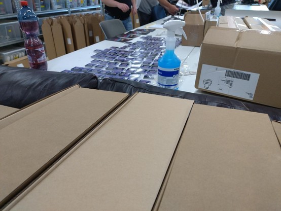Picture of boxes with posters and Why2025 stickers on a table to put into info packages.