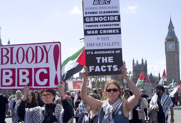 2 women carrying placards 'bloody bbc' and 'avoiding these words -long list including genocide-, it's not impartiality, these are the facts'
