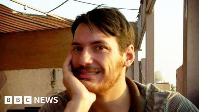 Picture shows Austin Tice in Egypt circa 2012 (exact date not known)

The image captures an outdoor setting with a striped awning providing shade overhead. In the background, there's a beige wall adorned with a decorative element and a light fixture, along with structural features like pillars and beams—suggesting this might be a patio or terrace. The lighting indicates it's likely daytime. A man, with a light beard and brown hair, is seated, wearing a striped shirt, with one hand resting on their face in a relaxed posture.