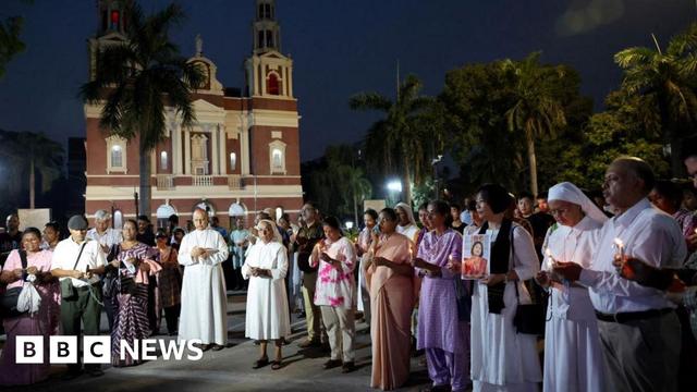 People hold candles as they attend a vigil for the victims of an Air India plane crash
