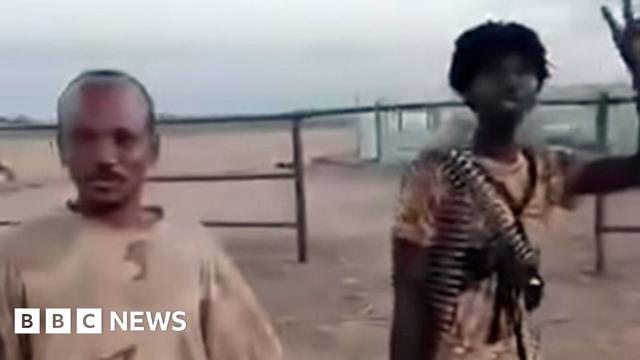 A screengrab of two RSF fighters in el-Fasher's cattle market - one with a belt of ammunition around his neck holds up a victory sign A screengrab of two RSF fighters in el-Fasher's cattle market - one with a belt of ammunition around his neck holds up a victory sign