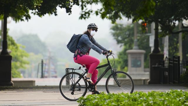Une personne porte un masque alors qu'elle fait du vélo.
