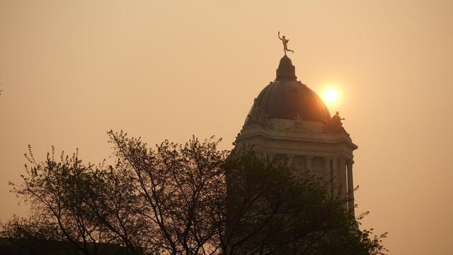 Le Palais législatif du Manitoba au lever du soleil sous la fumée des feux de forêts.