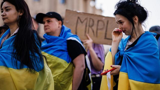 People draped in Ukrainian flags remembering the 2022 bombing of the Mariupol Theatre. | Clemens Bilan/EPA