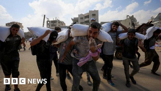 Palestinians carry bags of flour from a UN aid convoy that crossed into northern Gaza on 20 July 2025