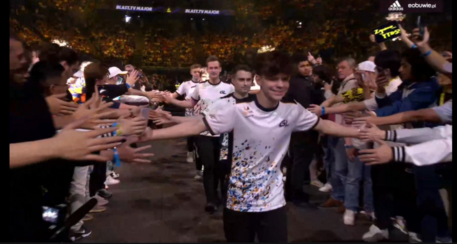 Polski kapitan zespołu GamerLegion prowadzący zespół na scenę i zbijający piątki i pozdrowienia z fanami po obu stronach ścieżki na scenę