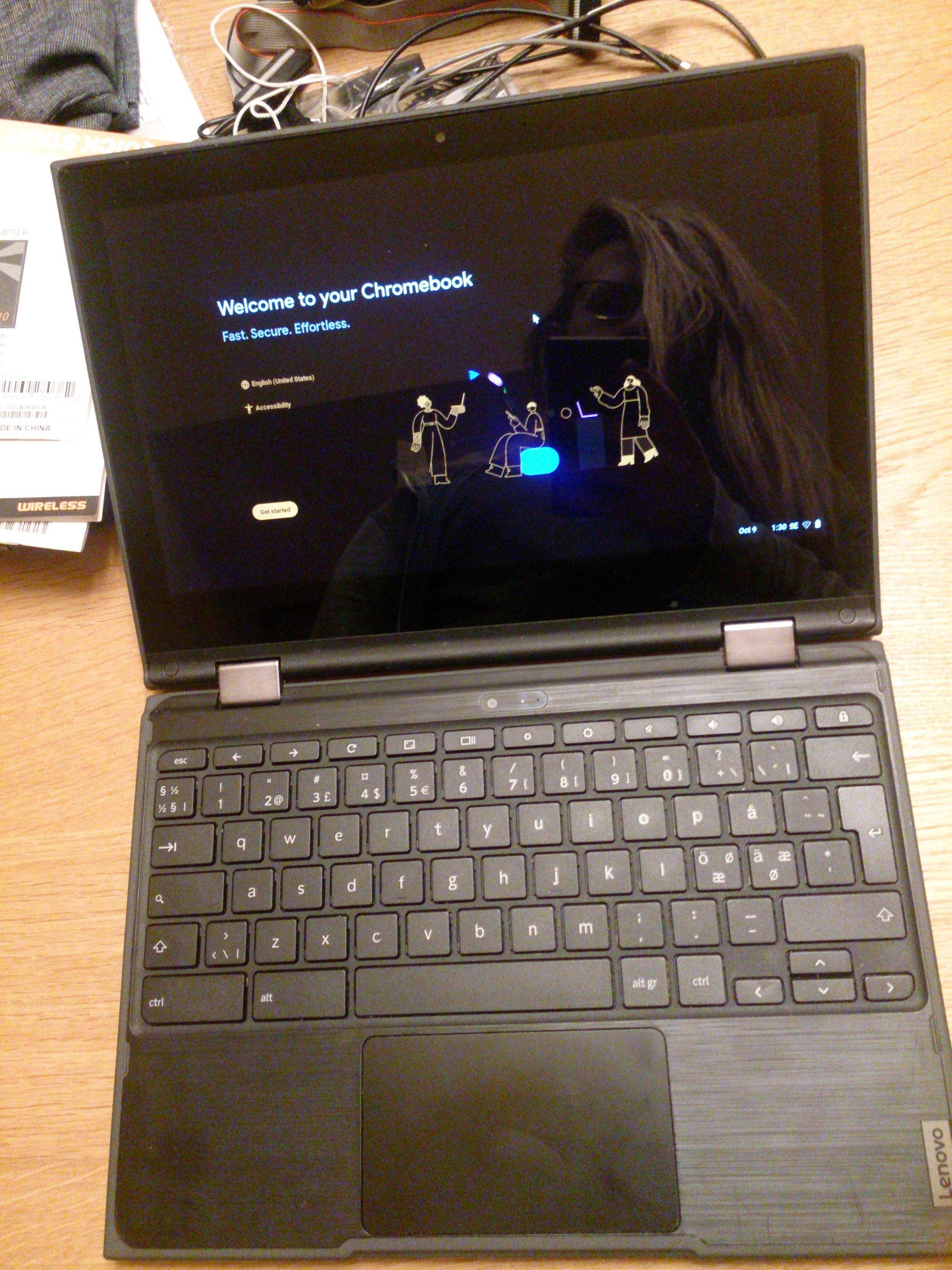 Chromebook open, I'm sitting pretty in the reflexion; there's a camera above the screen and above the keyboard; the keyboard itself is swedish and decroted: there are two extrmely wide keys to the left of the space bar (ctrl and alt), the ISO enter is half a key thin, the caps lock has a 🔍 on it, and the top row has an esc key, then a series of 11 icons