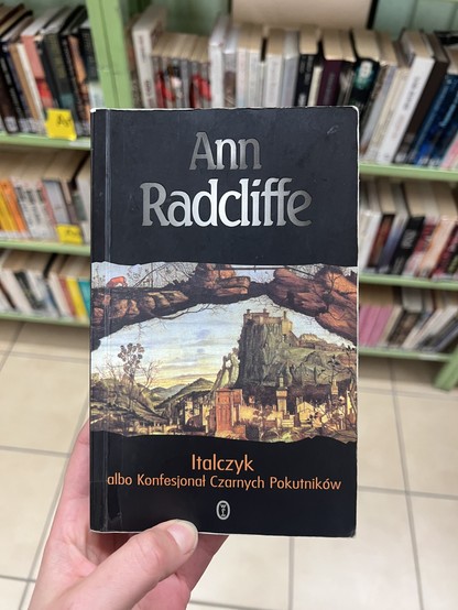 Książka Italczyk Ann Radcliffe, zdjęcie zrobione w bibliotece na tle półek, tryb portretowy 