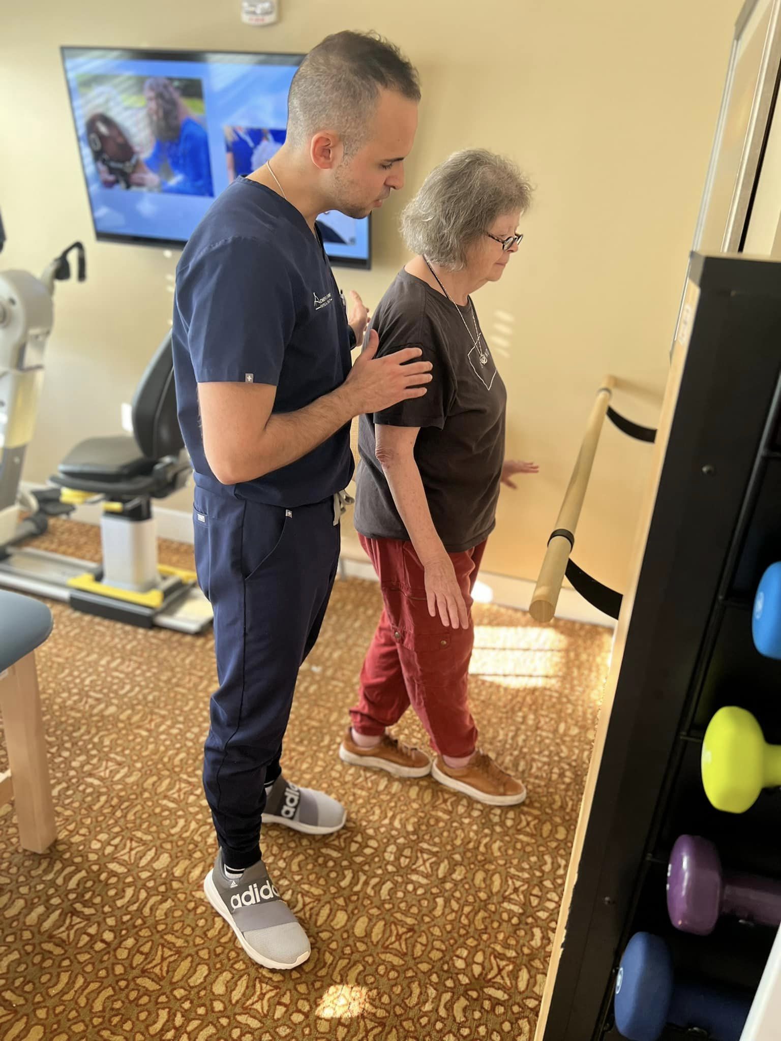 A physical therapist helping an elderly woman walk toe to toe